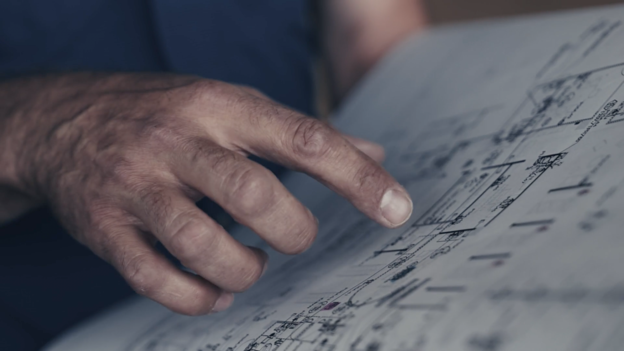 Gros plan sur des mains qui lisent des plans d'architecte, image tirée d'un film de marque monté par le monteur vidéo montréalais Victor Tamarit